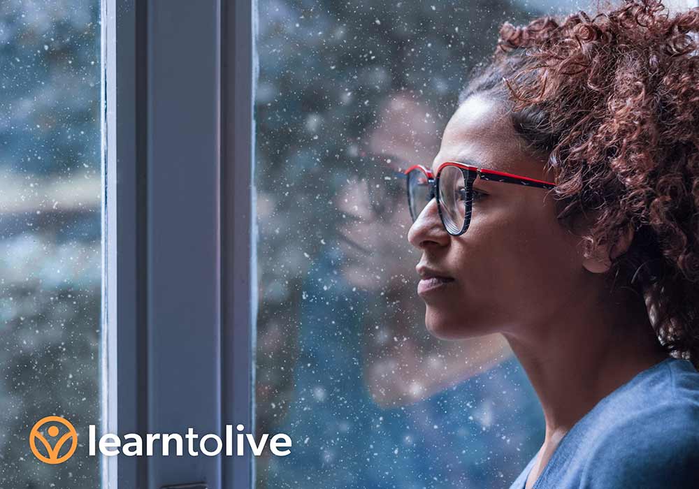 A woman looking thoughtfully through a snowy window