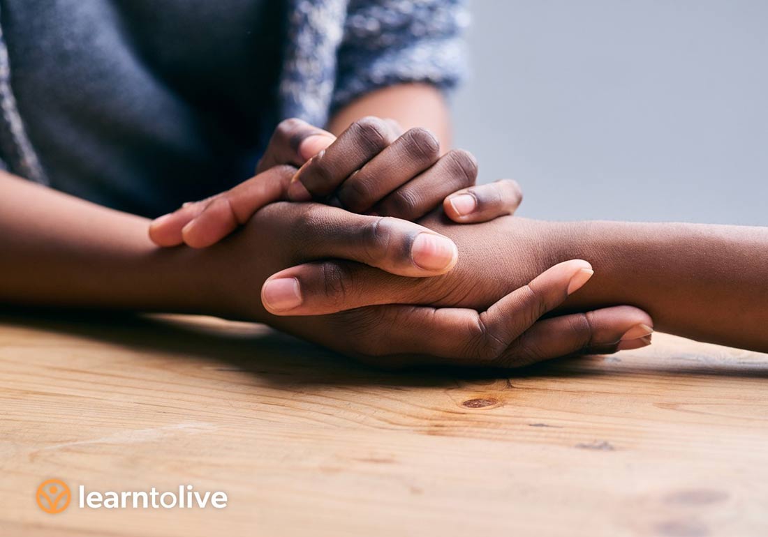Two people of color holding hands across a table