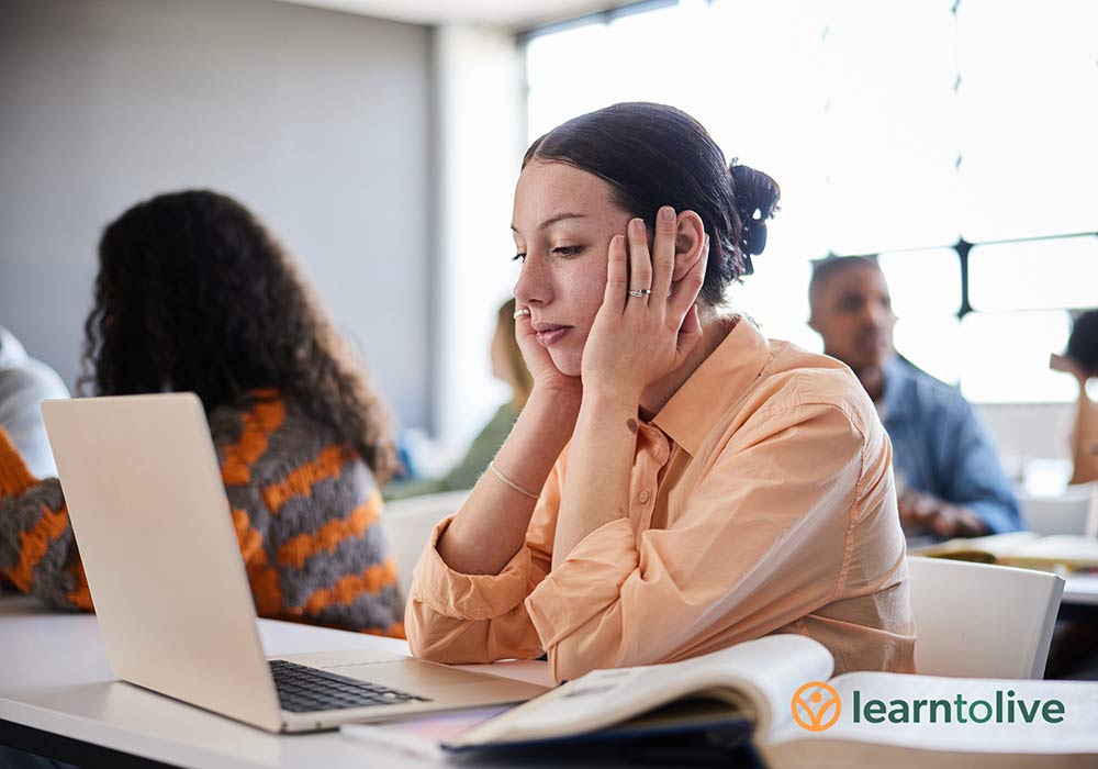 Young woman in class holding her head in her hands
